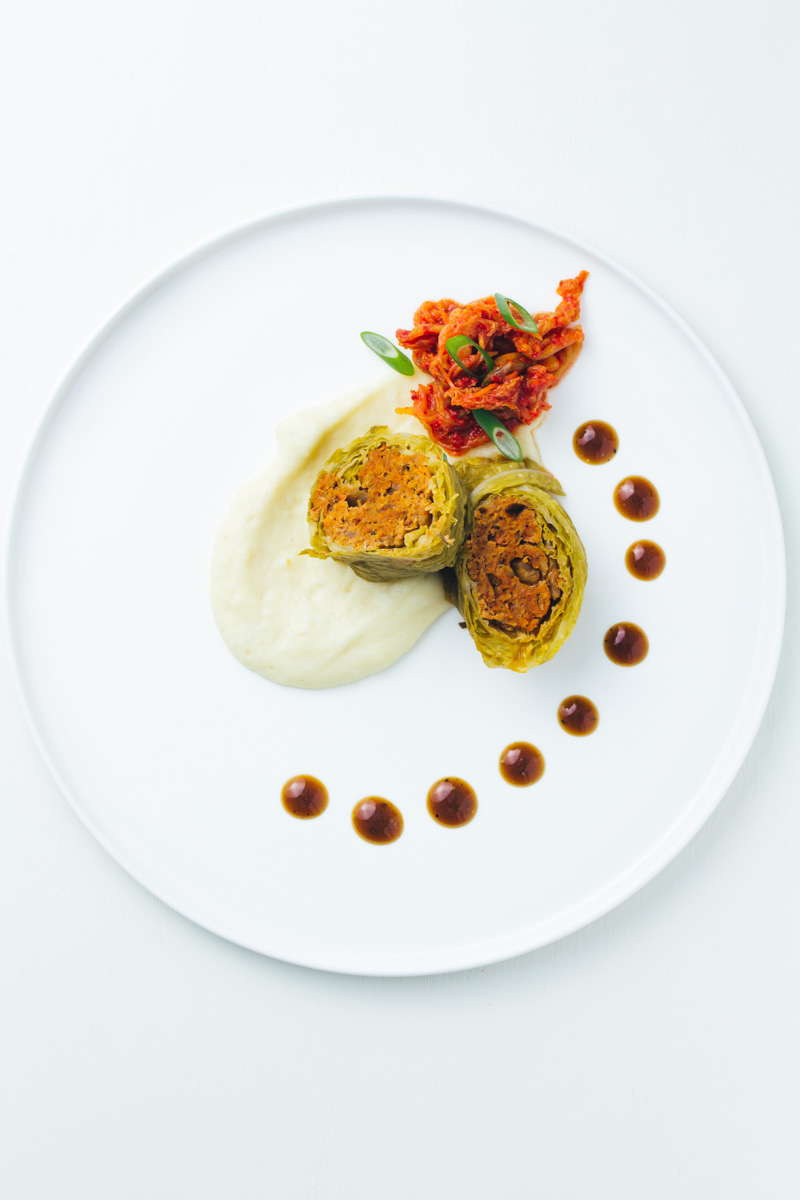 Kimchi-Wirsingroulade mit Topinamburpüree auf weißem Teller
