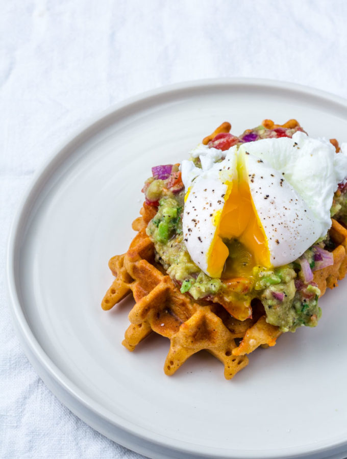 Aufgeschnittenes pochiertes Ei läuft über Cornbread Waffel