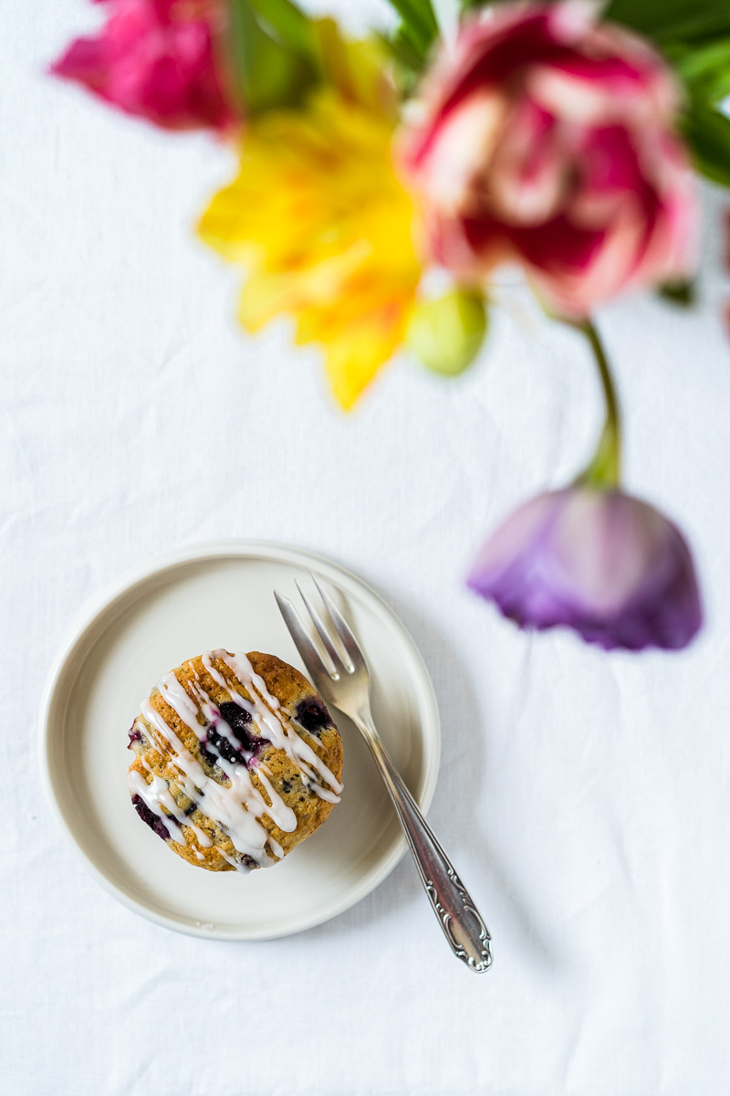 Zitronen-Blaubeer-Joghurt Muffin auf kleinem Teller und mit Blumen