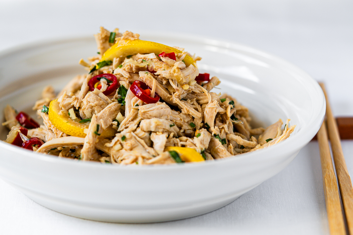 Chinesischer Zitronen-Hähnchensalat - 柠檬手撕鸡胸肉 in einer Schale mit Stäbchen