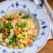 Miso-Gemüseeintopf mit Kohlrabi und Kartoffeln im blau-weißen Teller, mit Petersilie garniert, daneben ein Löffel